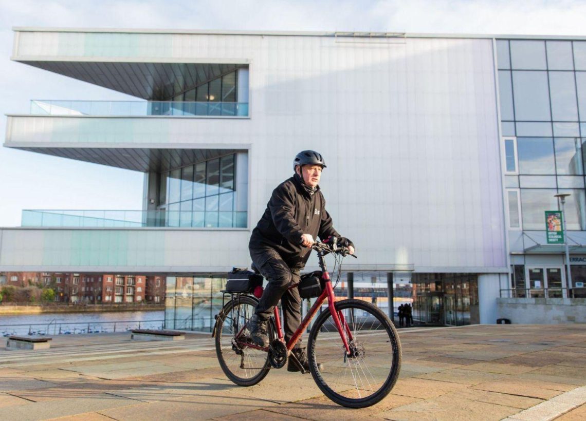 Employee riding bike out of ICC Belfast building as he makes use of the bike to work scheme.