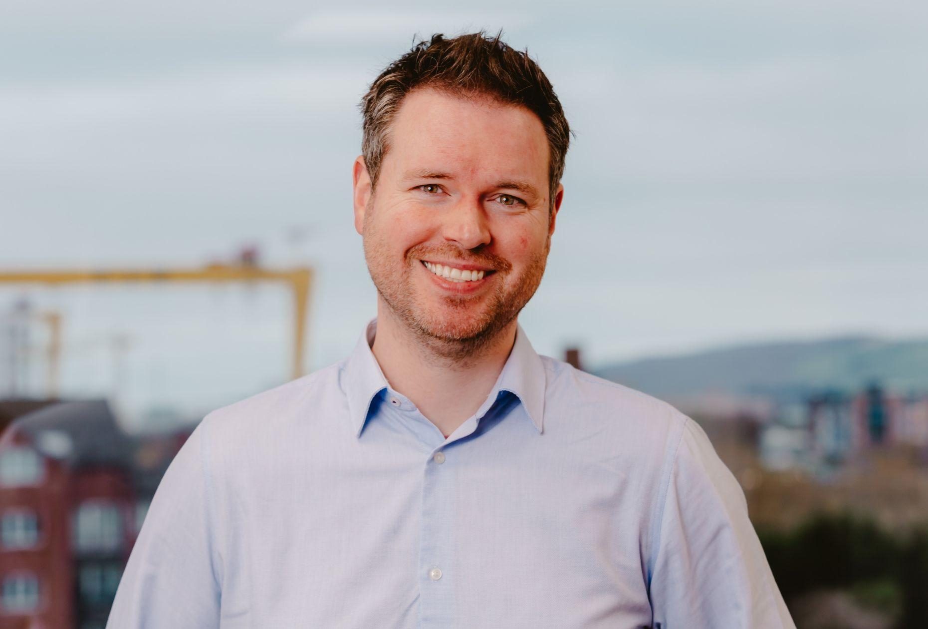 Man smiling for headshot against Belfast city skyline