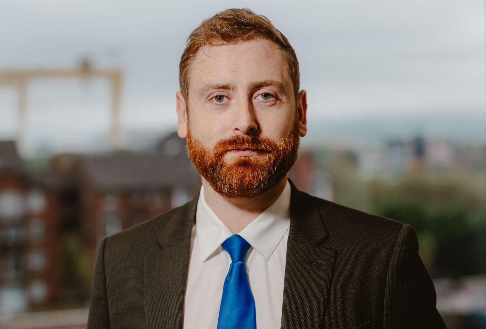 Man smiling for headshot against Belfast city skyline