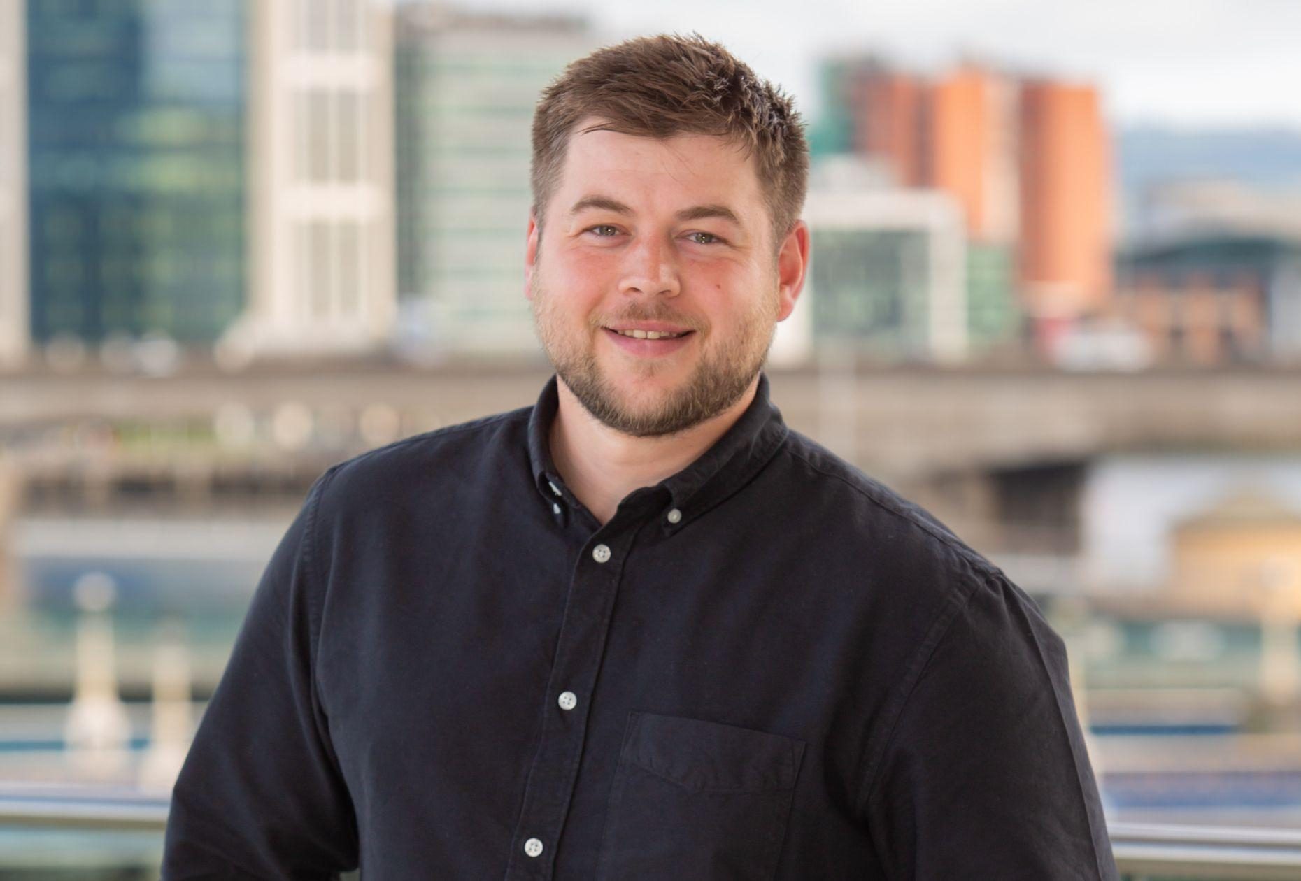 Image of man against Belfast city skyline backdrop