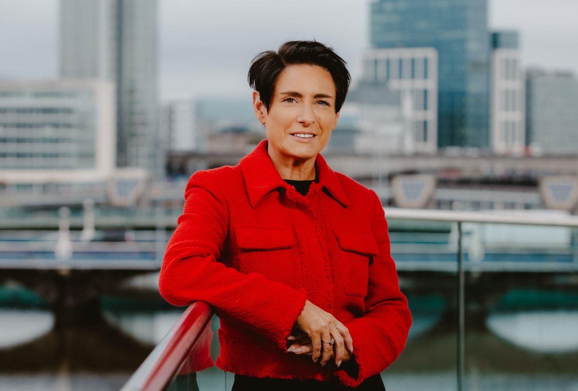 Woman smiling on a balcony for a photo in front of Belfast City skyline