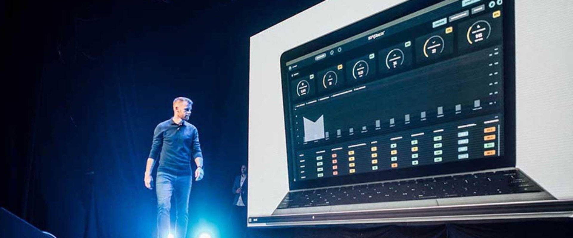 Man walking across on Waterfront Studio stage in front of screen showing dashboard