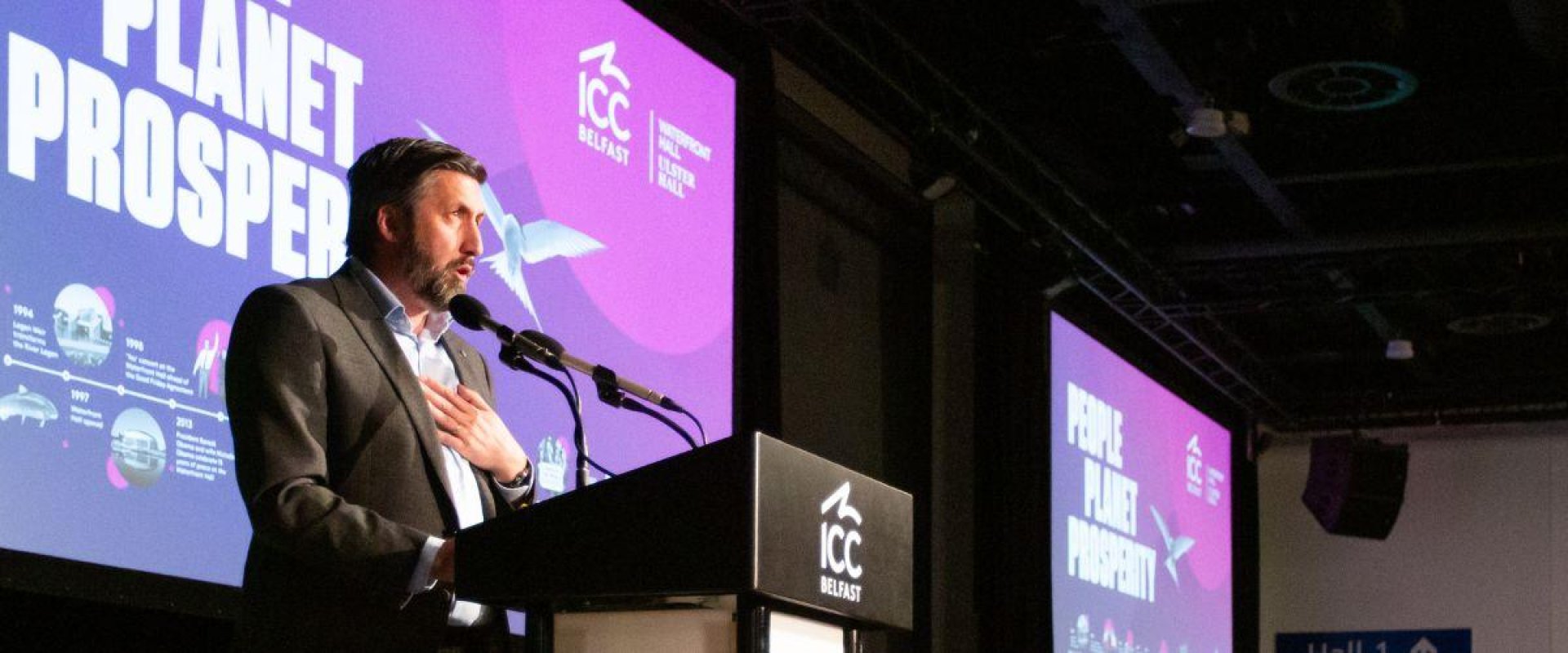 Man stands at lectern during Sustain Exchange conference for keynote speech
