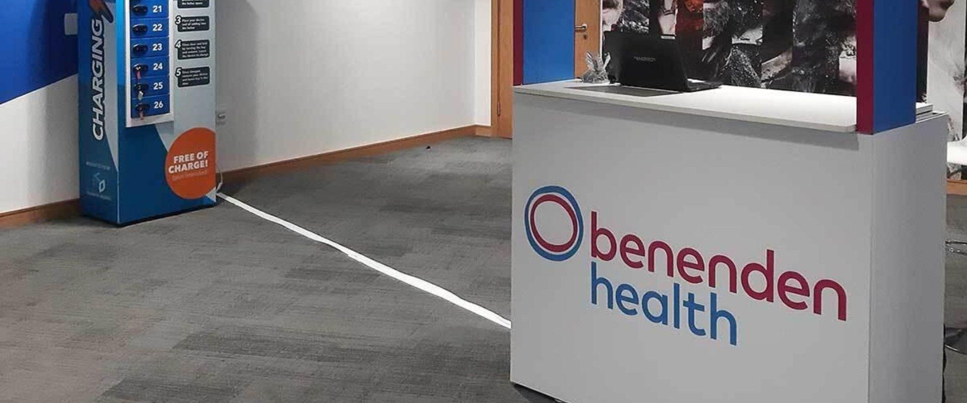 A well lit room with a Benenden Health stand at the conference which took place at ICC Belfast in 2019. A portable charger bank is also visible in the background.
