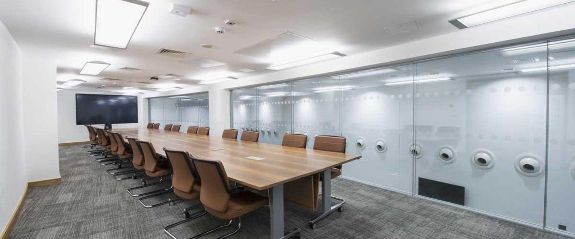 This image shows Boardroom 1 set up in boardroom style with a large TV screen at the far end of the table. This room as large windows which overlook Level 1 Foyer.