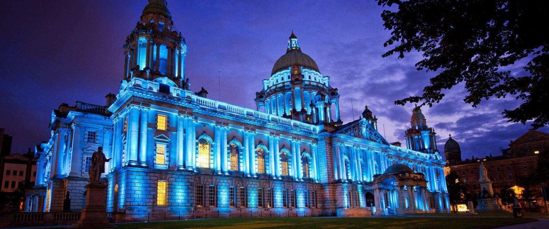 Image shows Belfast City Hall lit up at night