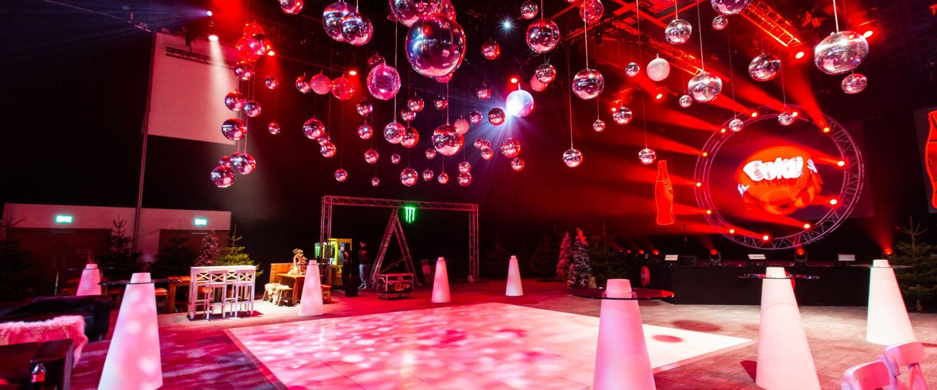 Hall 1 set up in après ski theme. There are pine trees, wooden tables, a dance floor and crystal balls hanging from the ceiling.
