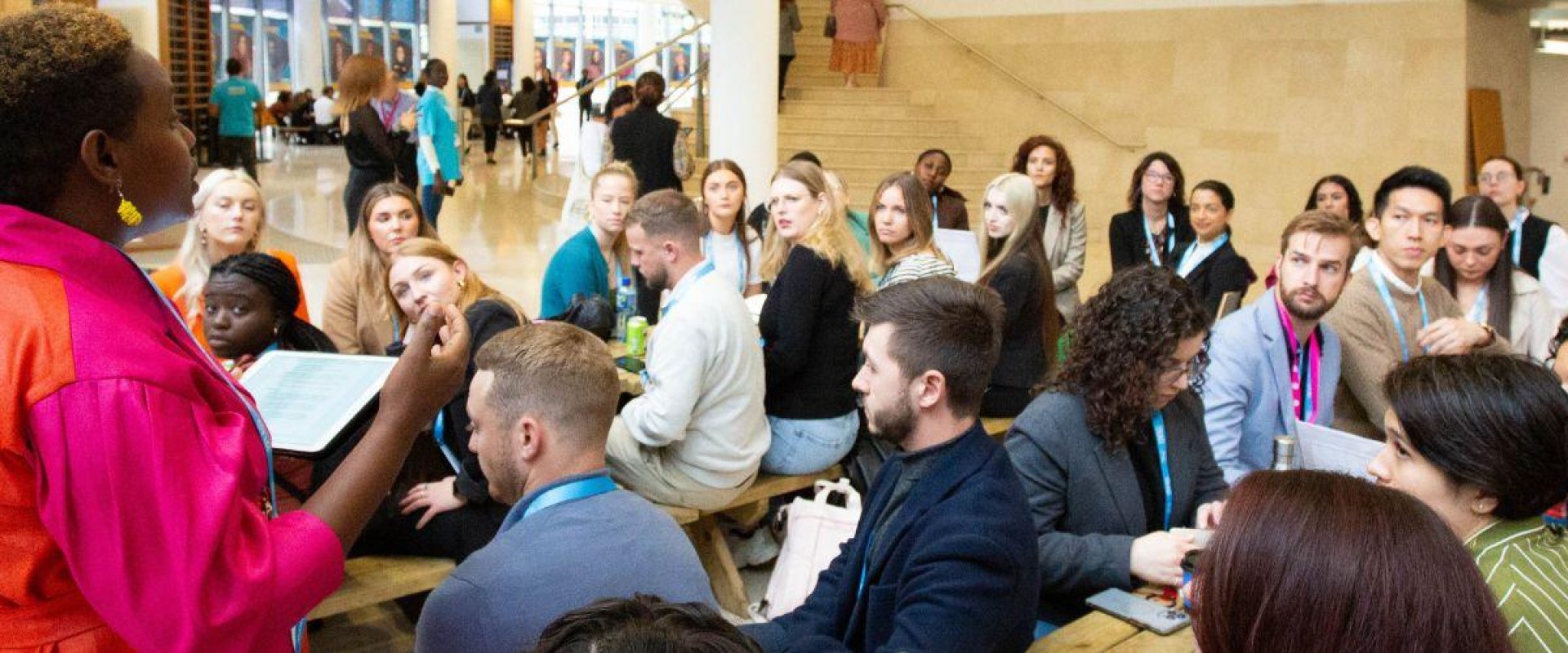 Multiple students sitting on benches listening to workshop coordinator