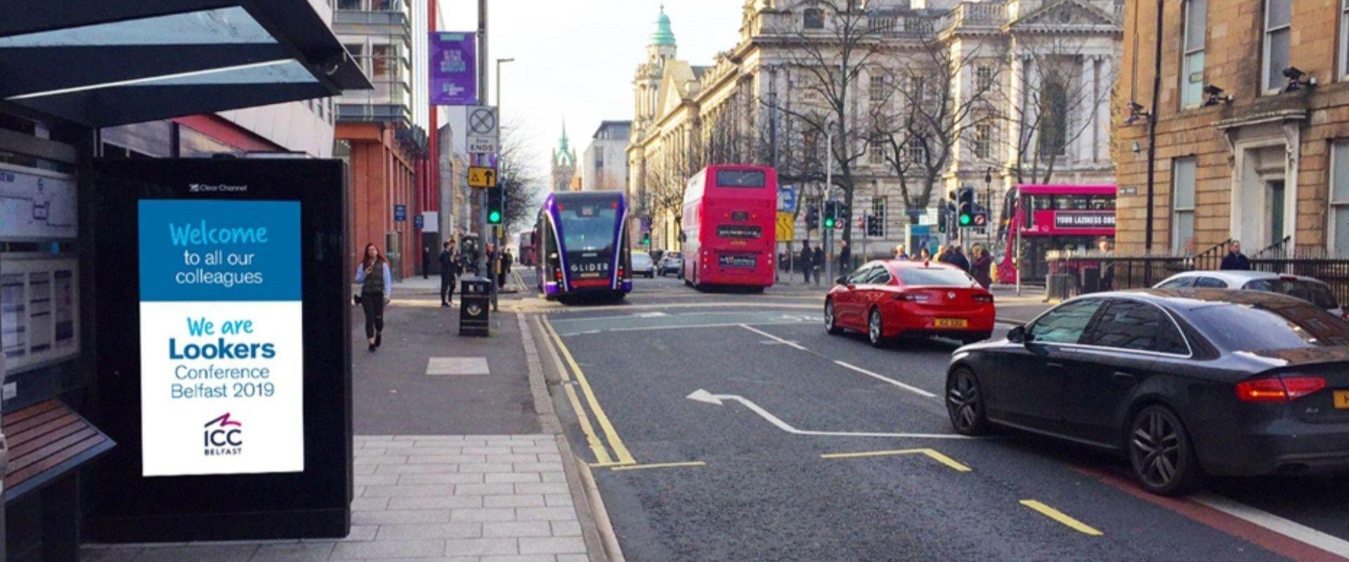 An outdoor advertisement at a bus stop on May St in Belfast city centre promoting We are Lookers conference Belfast 2019.