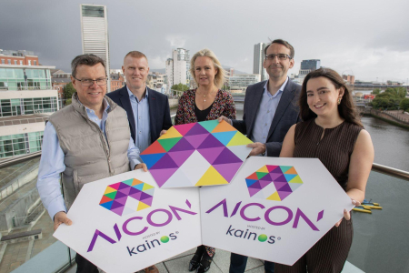 Group of people smile for press shot on balcony with Belfast city skyline in the background
