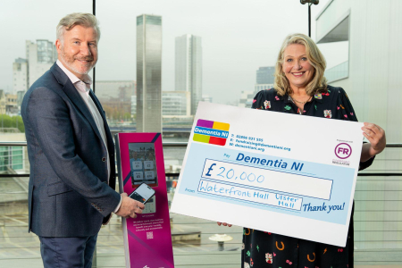 Man and woman smile for press shot holding cheque