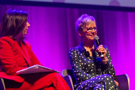 Woman smiles beside another woman on stage