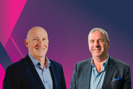 Image of two men in suits standing in front of purple background