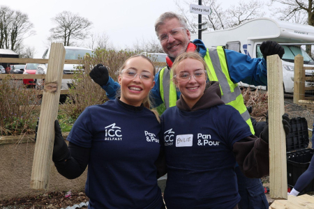 Two women and one woman dressed in work gear and protective glasses smile for press shot