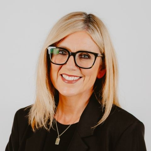 Women dressed in black with shoulder-length blonde hair and black framed glasses
