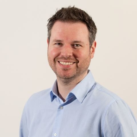 Man smiling for headshot against cream background