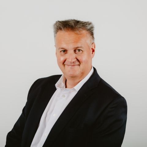 Man smiling for a photo in front of a white background
