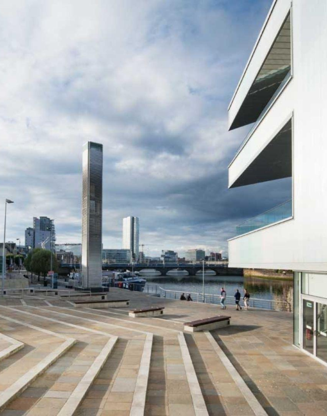 Image shows steps leading down to Riverside Entrance at ICC Belfast with balconies and Belfast cityscape in view.