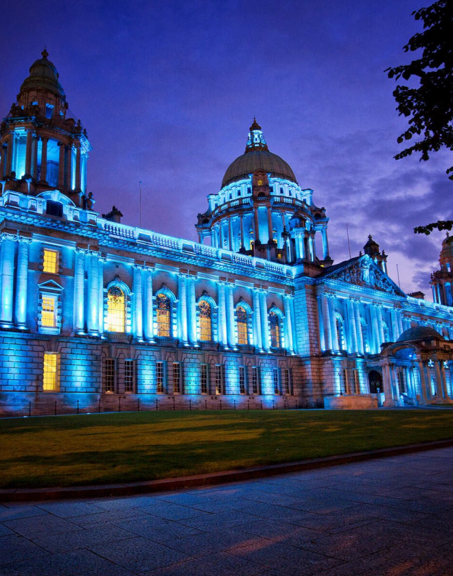 Image shows Belfast City Hall lit up blue at night