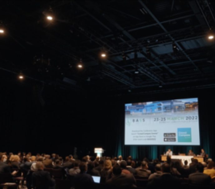People seated in front of large screen in hall