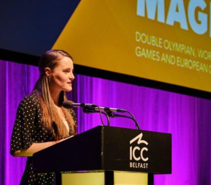 Ciara Mageean speaking at the SistersIn event in 2023. She is stood on stage at a podium with a microphone