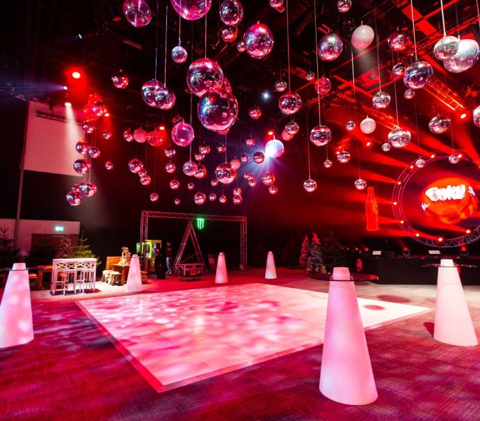 Hall 1 set up in après ski theme. There are pine trees, wooden tables, a dance floor and crystal balls hanging from the ceiling.
