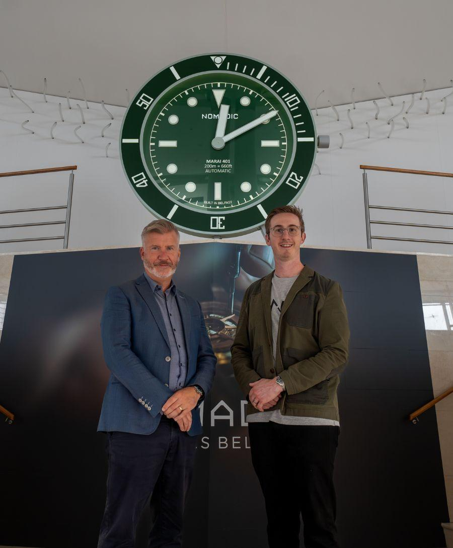 Two men smiling for press image in front of watch company activation