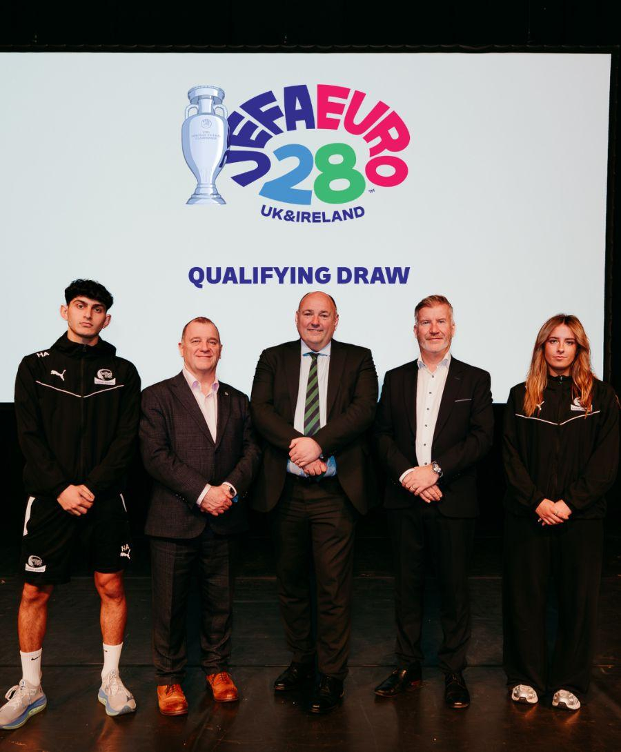 Four men and one women stand for a press shot against a white background with the UEFA Euro 2028 logo in colour displayed behind them