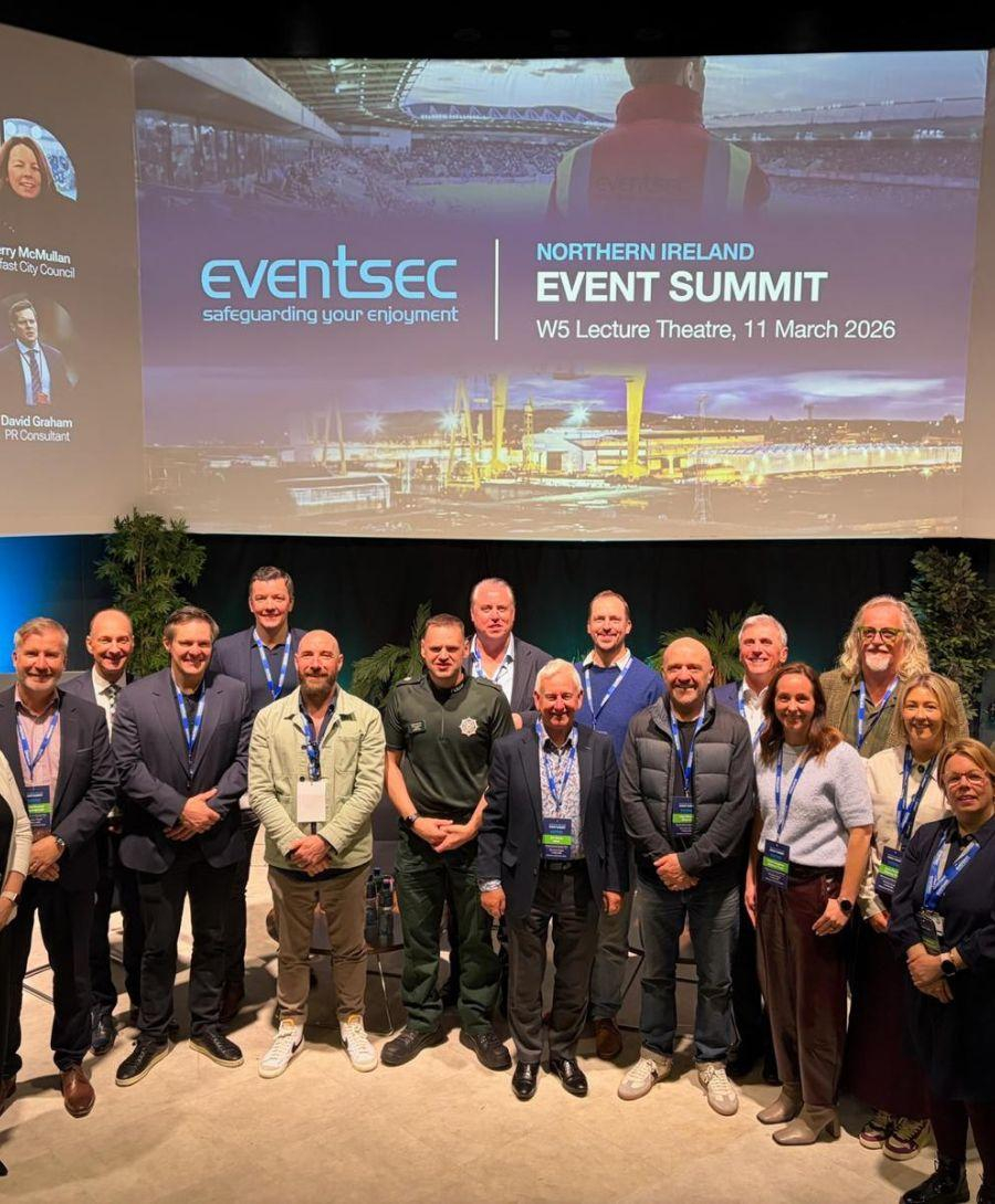 Group of people dressed in formal attire smile for press shot on stage