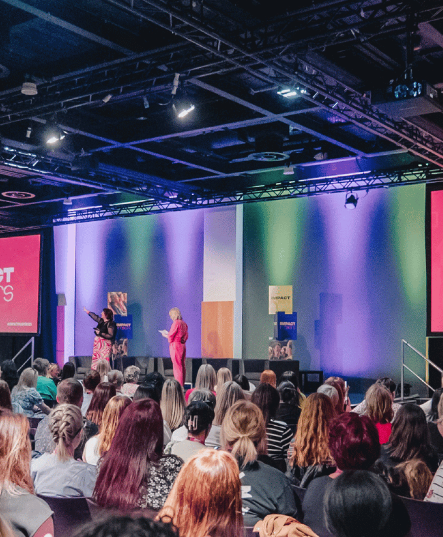 Impact Players on stage with a crowd of people in a conference