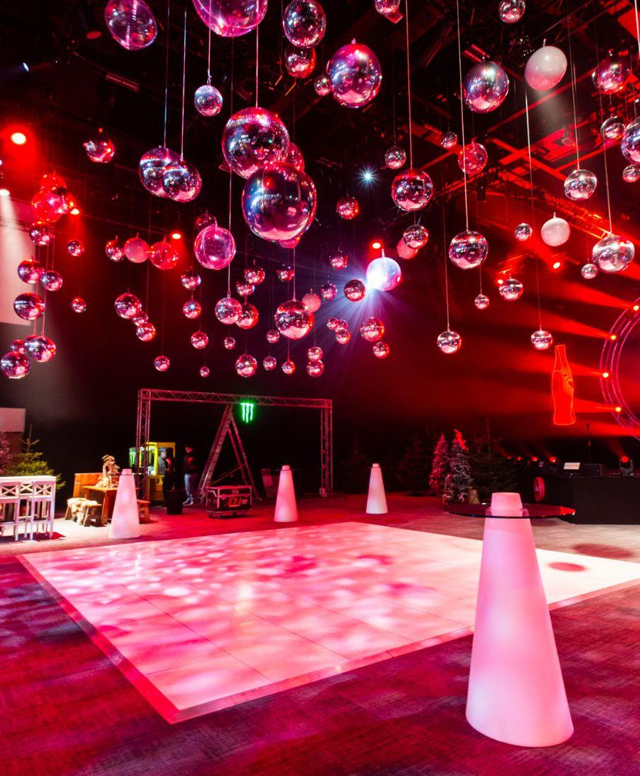 Hall 1 set up in après ski theme. There are pine trees, wooden tables, a dance floor and crystal balls hanging from the ceiling.