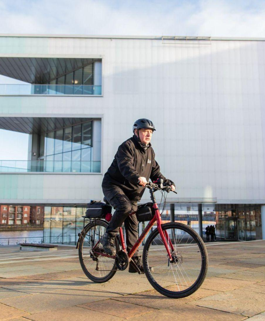 Employee riding bike out of ICC Belfast building as he makes use of the bike to work scheme.