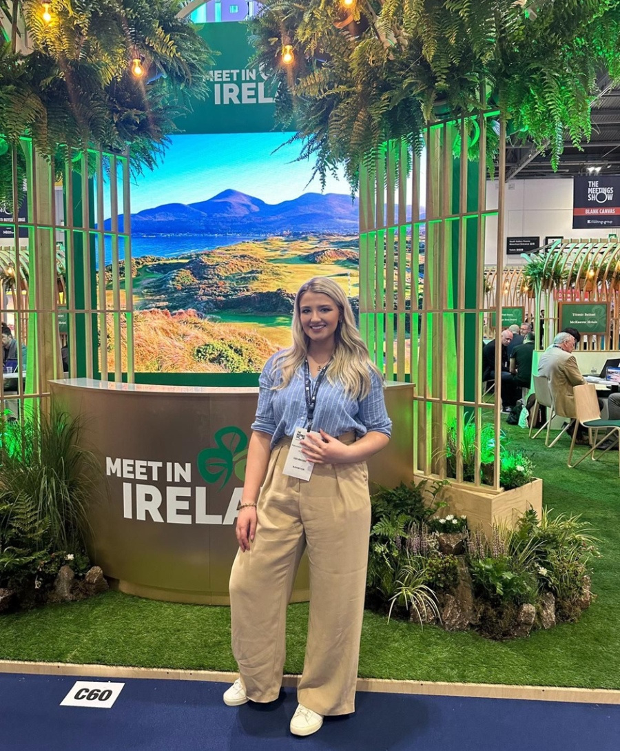 Antonia Willis at The Meetings Show 2024 in London posed in front of the Meet In Ireland stand.