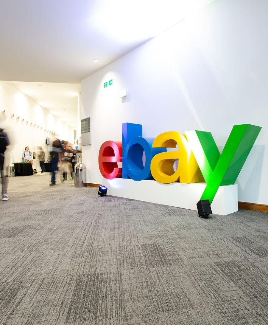 Branded eBay sign located outside Hall 2 with delegates walking by
