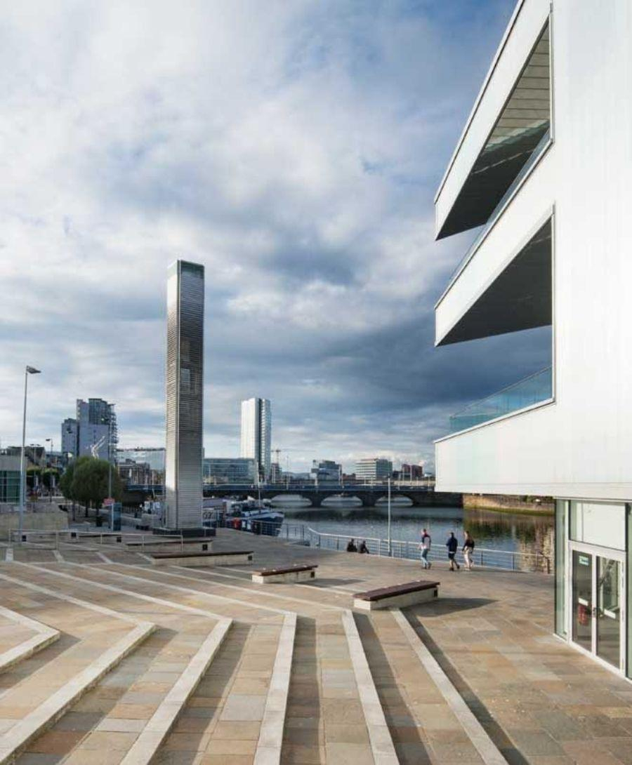 Image shows steps leading down to Riverside Entrance at ICC Belfast with balconies and Belfast cityscape in view.