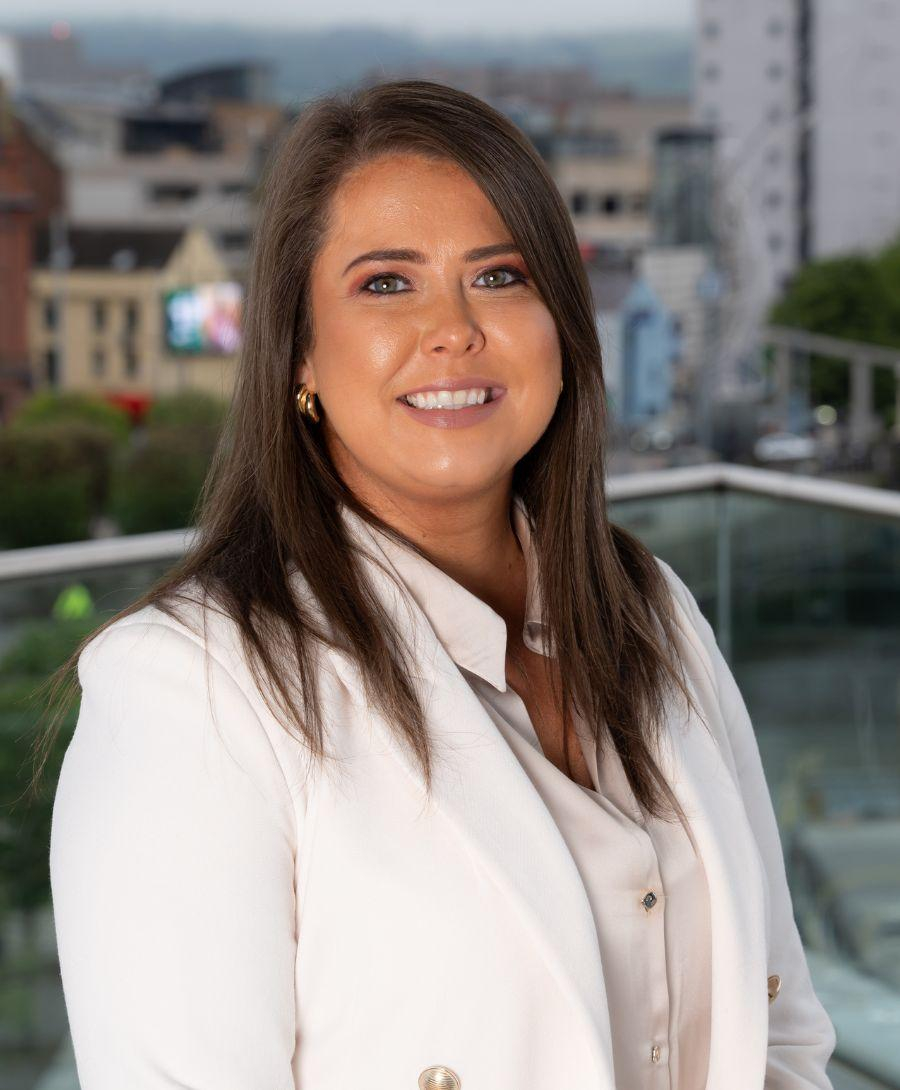Image of woman smiling on balcony with Belfast skyline in the background