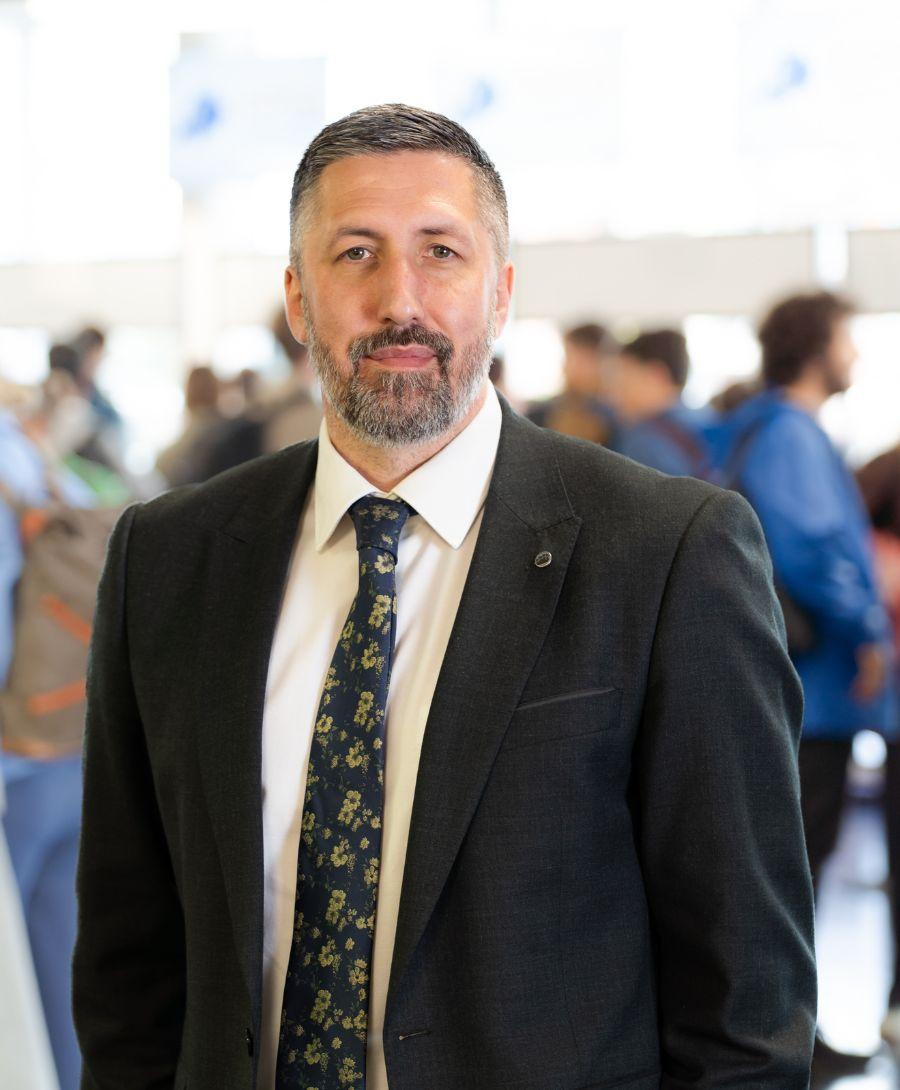 Image of man smiling in the mix of people walking and networking in the background