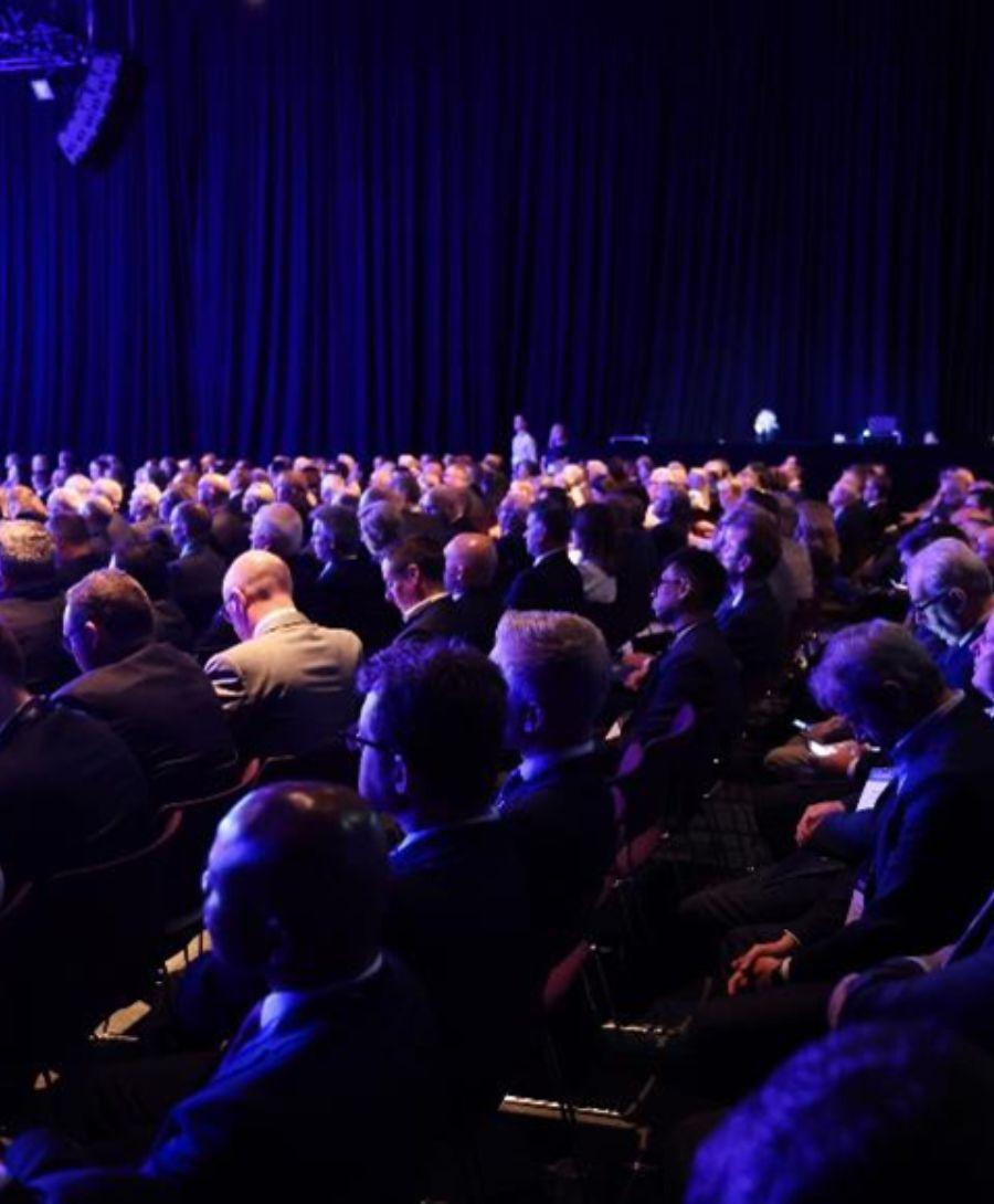 Hall 1 filled with seated delegates for the 2023 Investment conference, all facing the main stage.