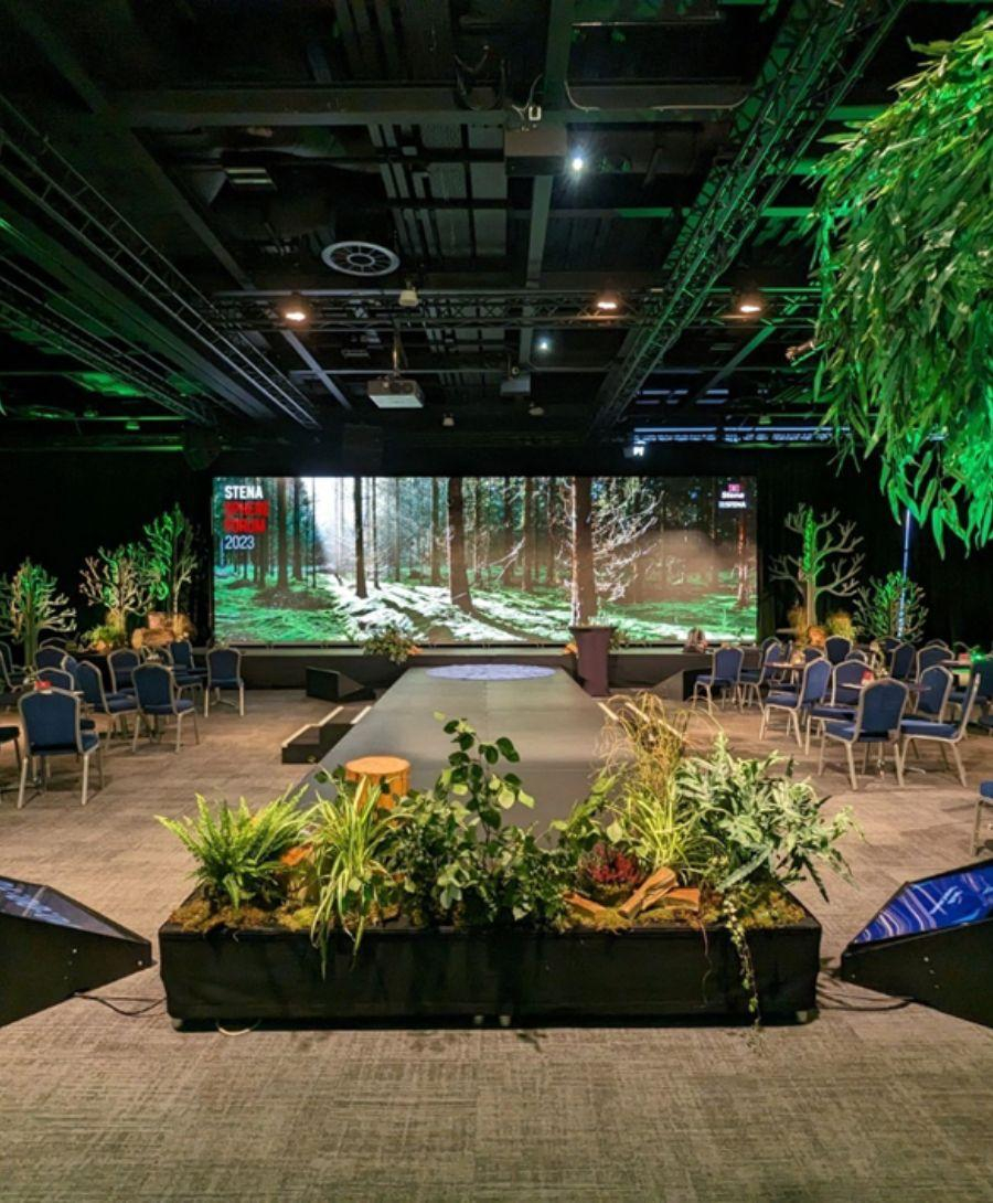 Hall 2 stage set for the delegates of the Stena Sphere Forum 2023 , with a large digital screen in the centre and tree design around the centre stage