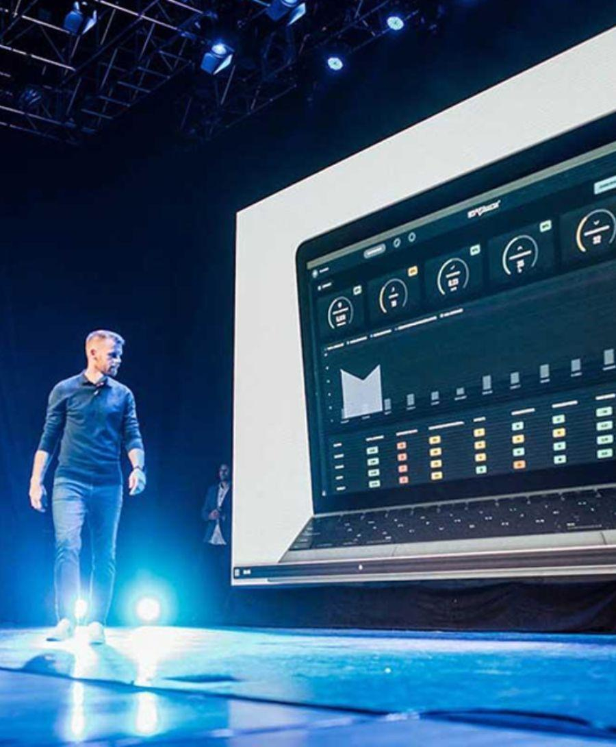 Man walking across on Waterfront Studio stage in front of screen showing dashboard
