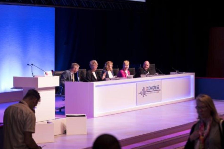 Image shows a panel of 5 people sat on stage.