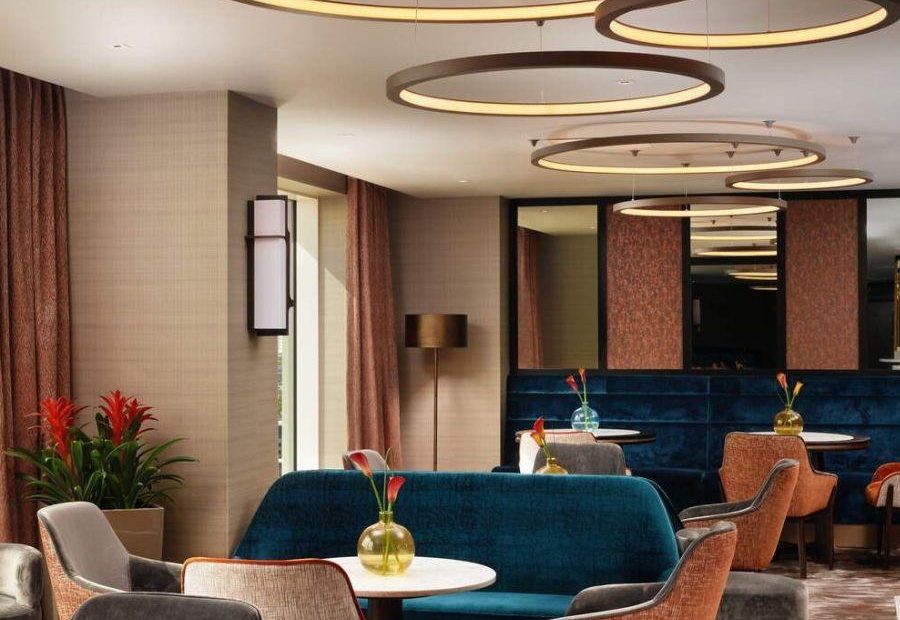 Circular tables with velvet chairs and sofas in carpeted restaurant with circular ceiling lights