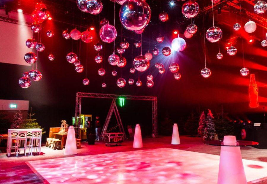 Hall 1 set up in après ski theme. There are pine trees, wooden tables, a dance floor and crystal balls hanging from the ceiling.