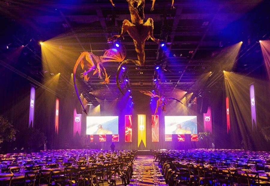 ICC Belfast, hall one,  game of thrones themed gala dinner set up with overhead hanging dragon and blue and pink beaming lighting