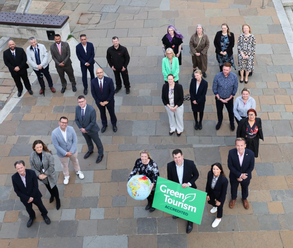 Image taken from birds eye view of people stood in a specific order to create the number '75' and holding a sign that reads, 'Green Tourism Accredited'