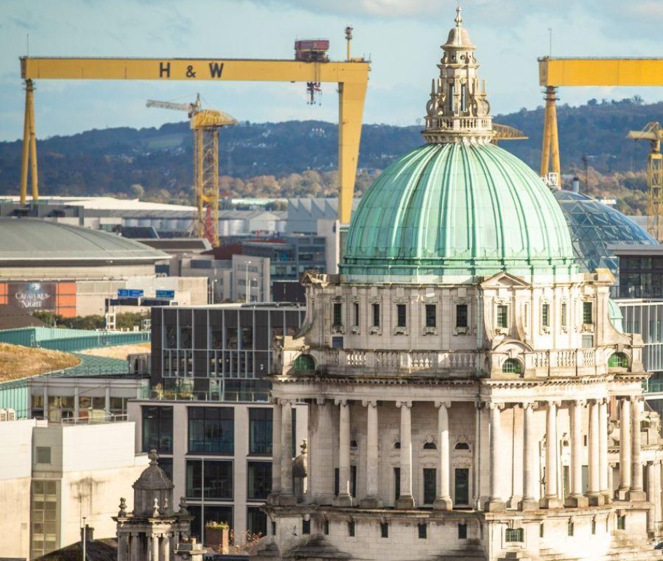 Image is taken from a height overlooking Belfast city with Belfast City Hall and Harland and Wolff cranes in focus